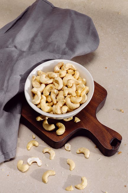 Top view of cashew nuts in a bowl on a wooden cutting board, perfect for healthy snack concepts.