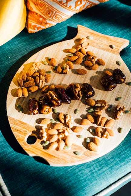 Top view of various dry fruits and nuts on a wooden board with bright sunlight.